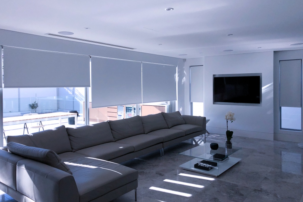 Roller Blinds are depicted in a living space for light dimming within the space. This project showcases one of the many projects completed by unique blinds in Sydney.