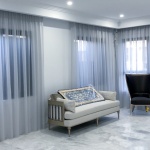 Grey coloured transparent sheer curtains are pictured in the living room of a Sydney home behind the beige coloured sofa.